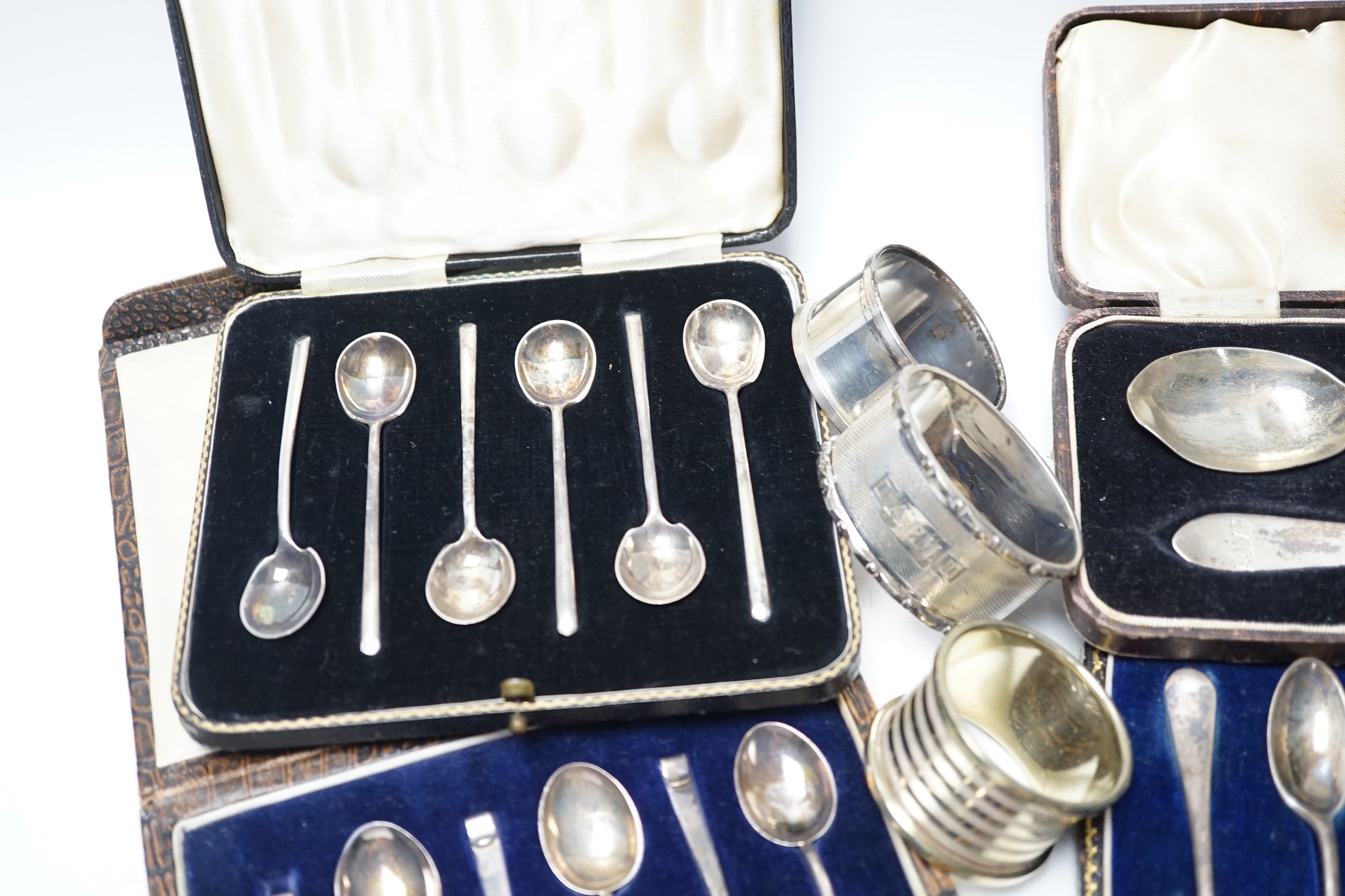 Four various silver serviette rings and a plated napkin ring, two small silver dishes, three various boxed sets of silver flatware and one part set of silver flatware.